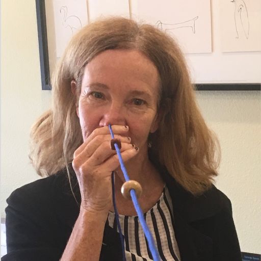 Lady with thick blond hair holding a Brock string looking at a brown bead. Her head is turned and tilted.